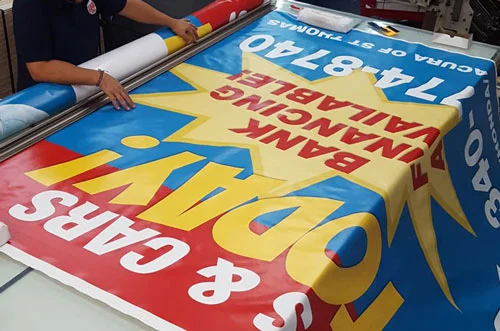 Super Large Size Banner - 8ft wide! The picture shows an 8ft-wide custom vinyl banner that is being manufactured on a large work table. Grommets and hems are being added to the vinyl banner