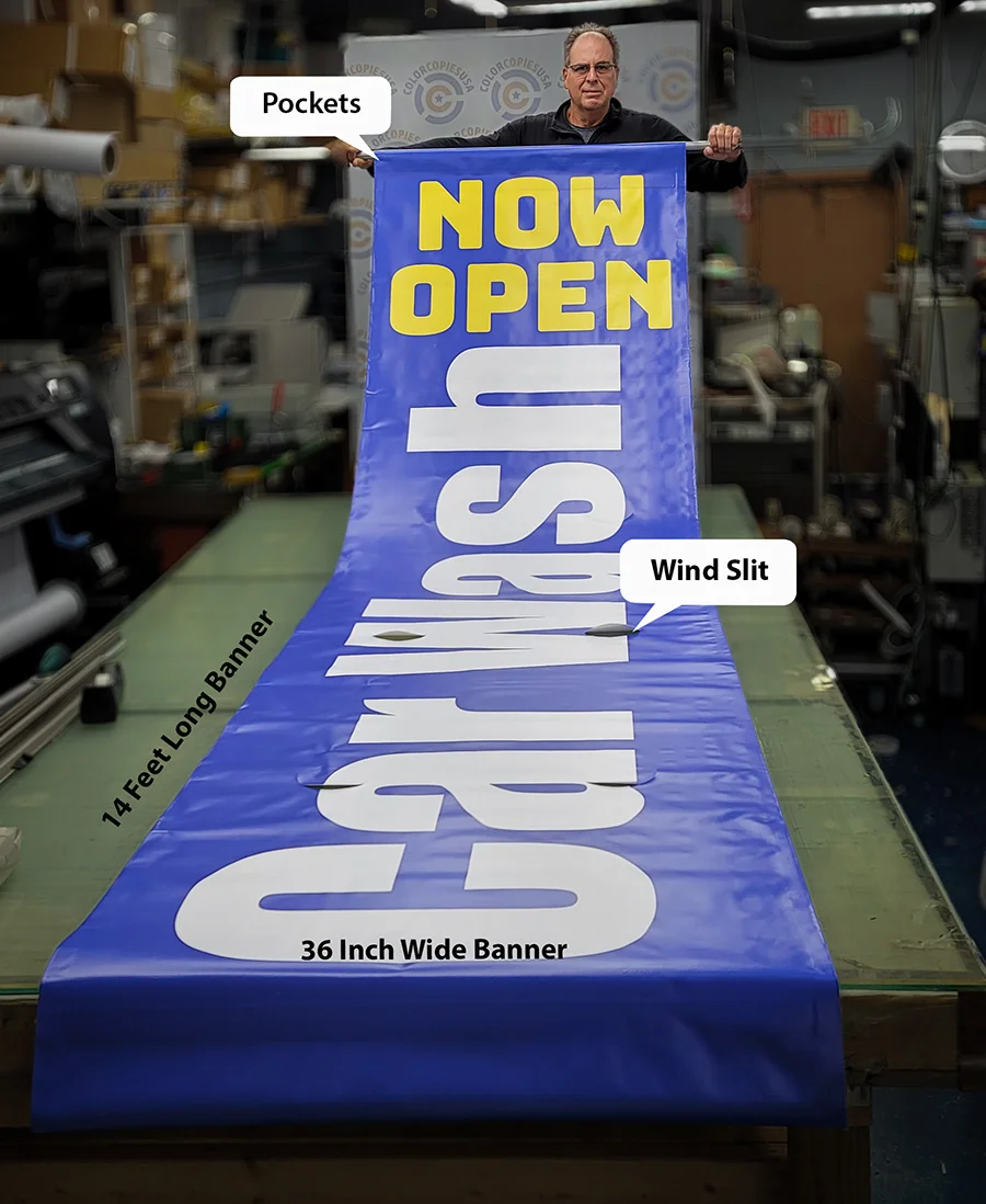 Extra-long Car Wash Now Open vinyl banner approximately 14 feet long shown next to a person at the ColorCopiesUSA production facility in Oakland Park Florida