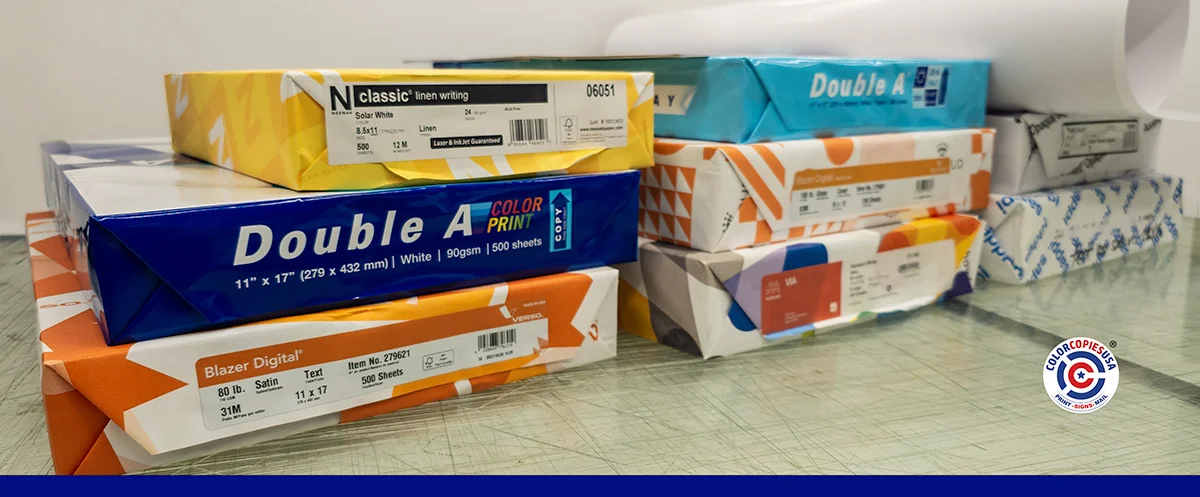 
Stacked reams of paper at the ColorCopiesUSA production facility showing linen writing, 80lb satin, Double A color print 11x17, and coated cover stock